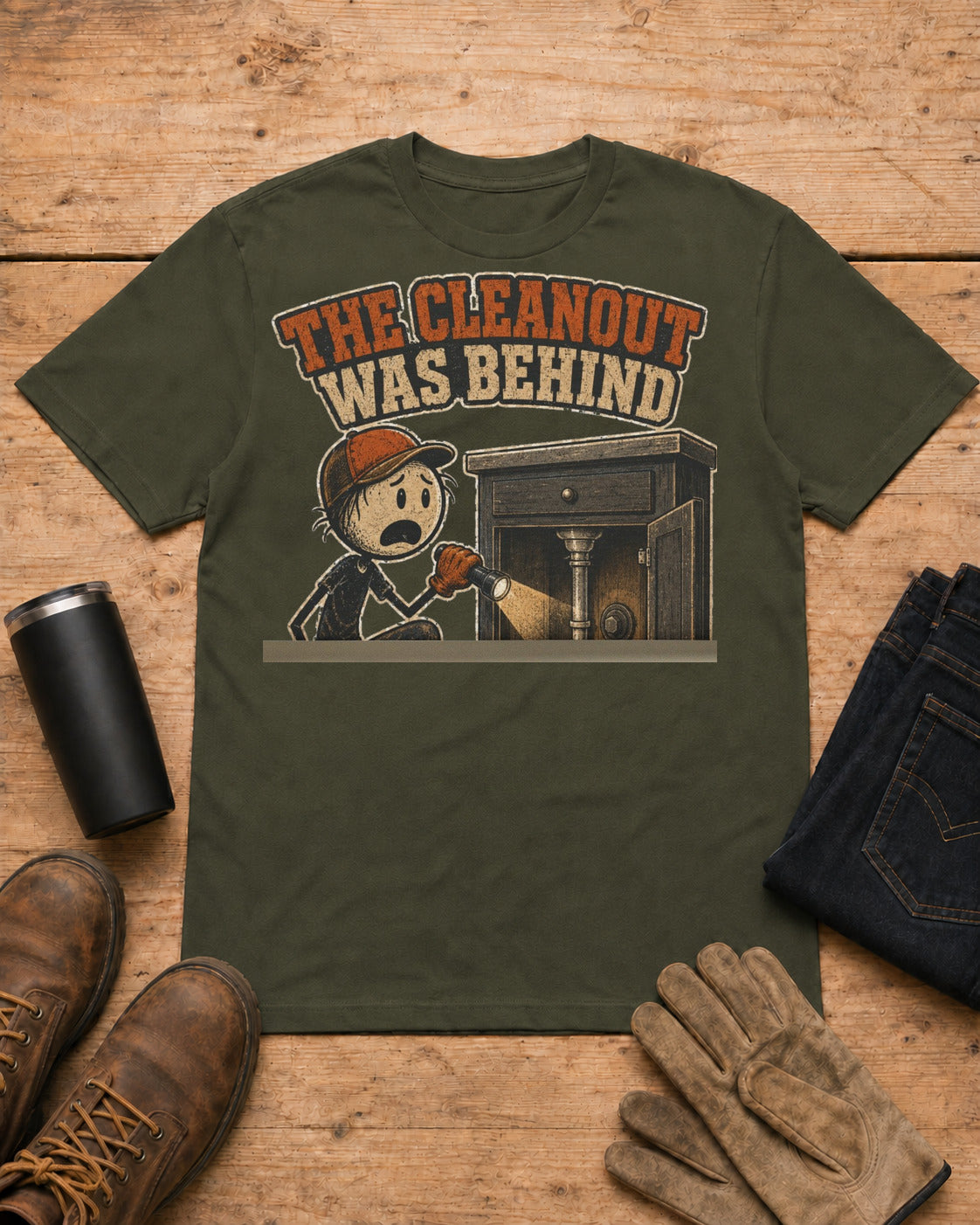 The Cleanout Was Behind the Cabinet Plumber T-Shirt in Military Green workbench flat lay